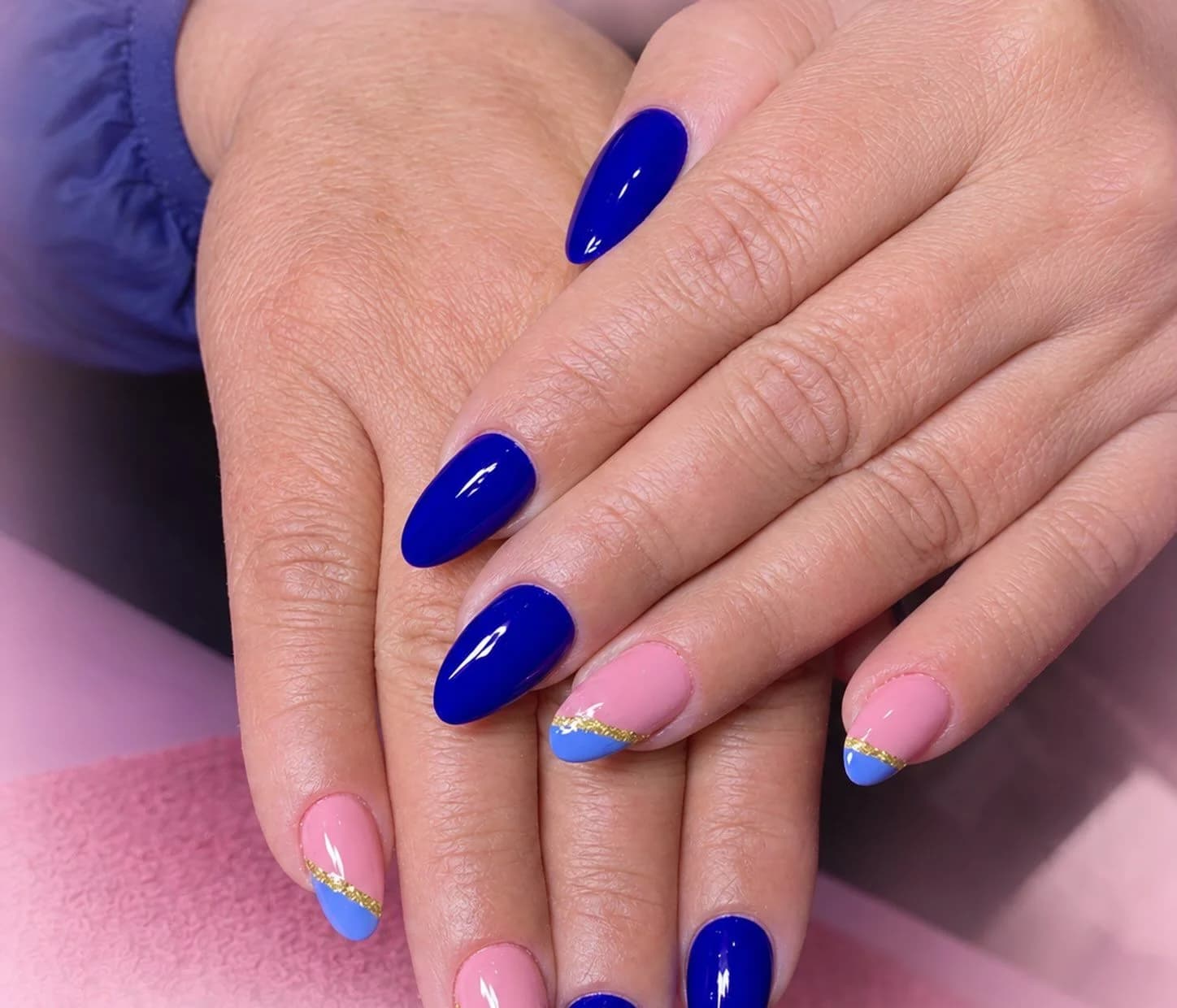 Unhas da Mariele em gel azul cobalto, com francês rosa e ponta azul cortada por glitter dourado